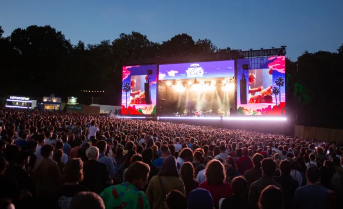 Tłum ludzi zgromadzony pod oświetloną sceną podczas plenerowego koncertu City Pop Waveswieczorem